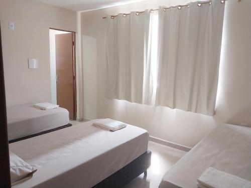 a white room with two beds and a window at Hotel hawaii in Campos dos Goytacazes