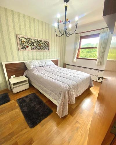 - une chambre avec un lit et un lustre dans l'établissement Duplex Vista da Serra, à Campos do Jordão