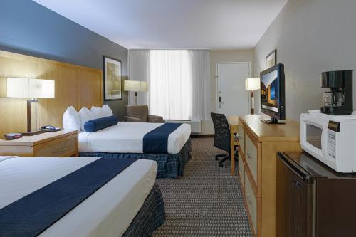 a hotel room with two beds and a flat screen tv at Travelodge by Wyndham Palm Springs in Palm Springs