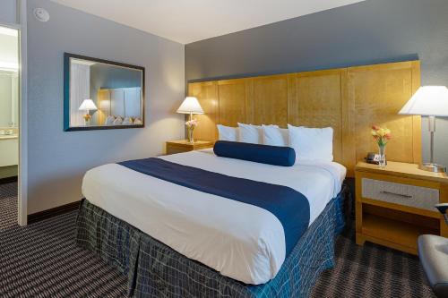 a hotel room with a large bed and a chair at Travelodge by Wyndham Palm Springs in Palm Springs