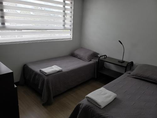a bedroom with two twin beds and a window at Apartamento La Floresta con todas las comodidades in Bogotá