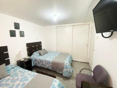 a bedroom with two beds and a flat screen tv at Ayli Apart Hotel in Arequipa