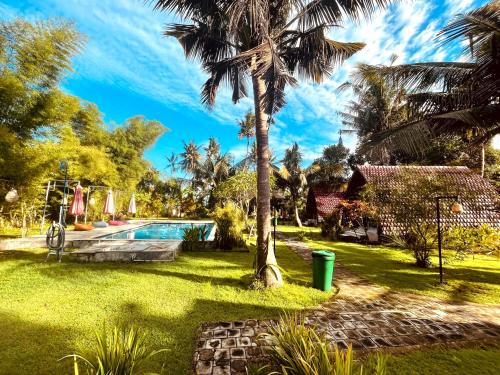 a villa with a swimming pool and palm trees at Apit Lawang Villas & Resto in Nusa Penida