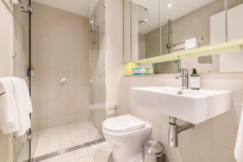 a bathroom with a toilet and a sink and a shower at KULA Docklands in Melbourne