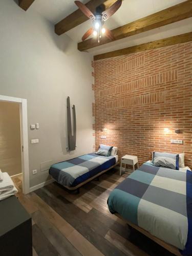 a bedroom with two beds and a brick wall at Las Gavias in Matapozuelos