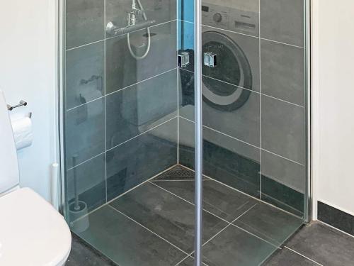 La salle de bains est pourvue d'une douche avec une porte en verre. dans l'établissement Holiday home Melby VI, à Melby