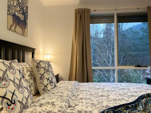 1 dormitorio con cama y ventana grande en Golfview Villa, en Warburton