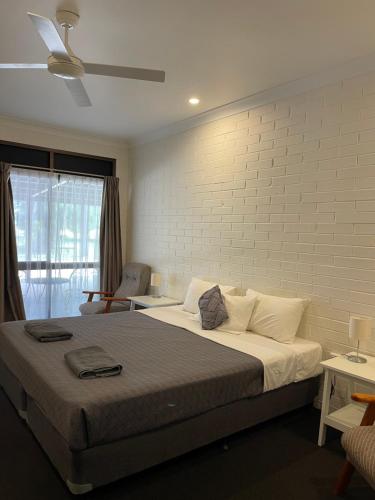 1 dormitorio con 1 cama grande y pared de ladrillo en Albert Park Motor Inn-KING BEDS-POOL-SHADED PARKING, en Longreach