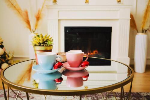 a coffee table with three cups on it with a fireplace at Stan na dan "Apartman Purple" in Banja Luka