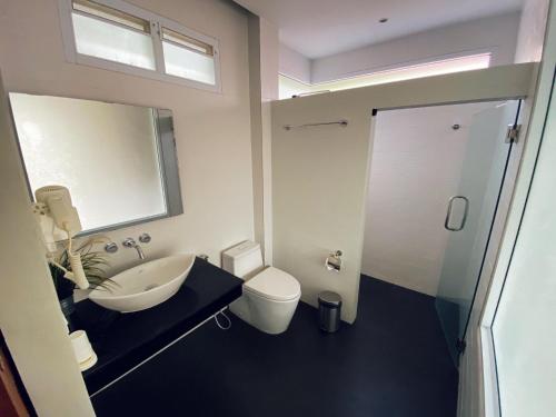 een badkamer met een wastafel, een toilet en een spiegel bij Silver Beach Resort in Lamai