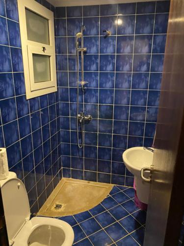 a blue tiled bathroom with a toilet and a sink at Studio in Porto Sharm in Sharm El Sheikh