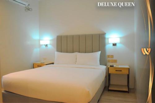 カルバヨグにあるWest Prime Hotelのベッドルーム1室(白いベッド1台、ナイトスタンド2台付)