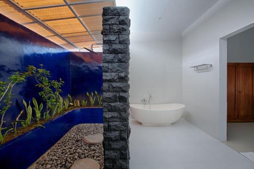 a bathroom with a stone pillar with a bath tub at My Villa and Resort Canggu in Canggu