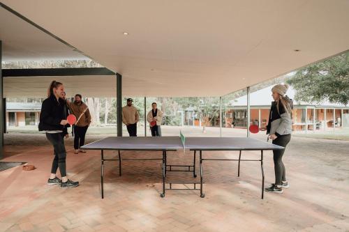 a group of people standing around a ping pong table at Hunter Valley Retreat in Quorrobolong