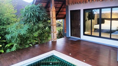 a house with a wooden floor and a swimming pool at Rongna Villas in Ko Yao Noi
