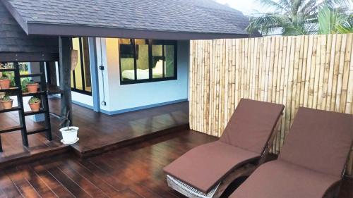 a porch with two chairs and a door on a house at Rongna Villas in Ko Yao Noi