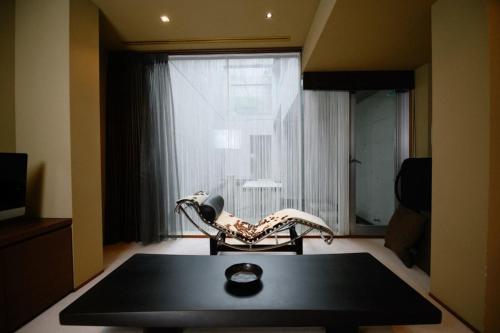 een woonkamer met een stoel, een tafel en een raam bij Azabu Modern House in Tokyo