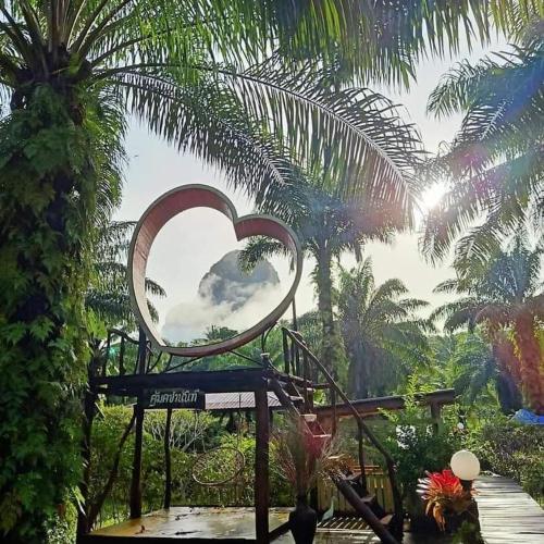 a mirror in the shape of a heart in a garden at Koom Kachanaan in Ban Nong Thale