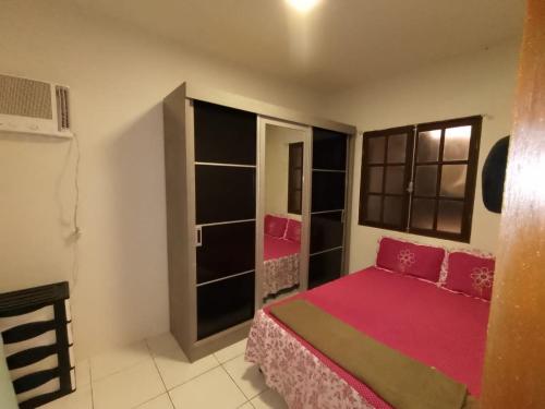 Un dormitorio con una cama rosa y algunos estantes en Casa Lua, en Ilhabela