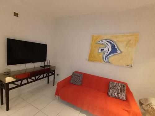 sala de estar con sofá rojo y TV de pantalla plana en Casa Lua, en Ilhabela