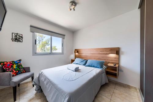 1 dormitorio con 1 cama, 1 silla y 1 ventana en Av Colon 1750 - B Alberdi Edificio con Cochera y Pileta en Córdoba