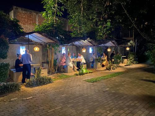 a group of people sitting at tables in a garden at night at Hotel Tinaya in Dambulla