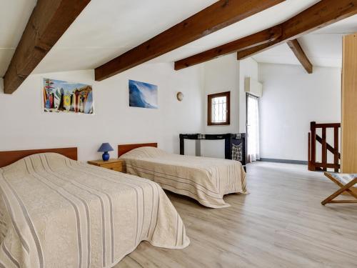 deux lits dans une chambre aux murs blancs et au parquet dans l'établissement Maison 5 pers. à Biscarrosse - Calme, proche plages, jardin, terrasse, parking - FR-1-521-25, à Biscarrosse-Plage