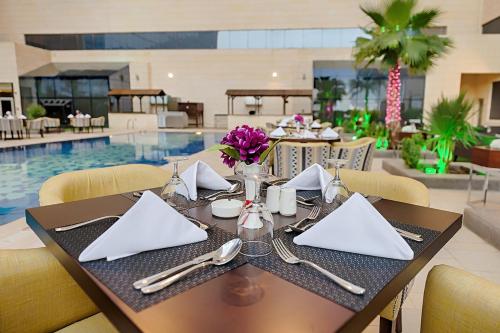 a dining table with white napkins and utensils and a pool at Makkah Al Aziziah in Makkah