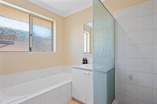 Baño blanco con bañera y lavamanos en Bea-Vic Home. Your home away from home., en Kalgoorlie