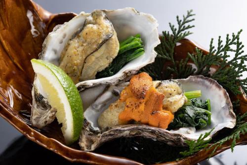 a bowl of oysters with a slice of lime at Onomichi Hansei in Onomichi