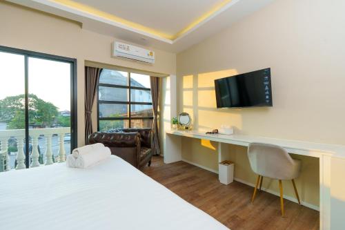 a hotel room with a bed and a desk and a television at Calinton Hotel in Udon Thani