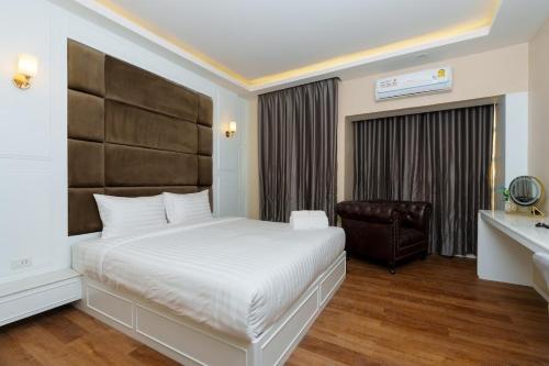 a bedroom with a bed and a desk and a chair at Calinton Hotel in Udon Thani