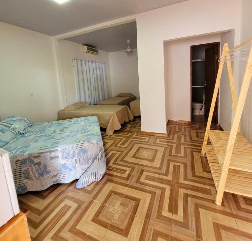 a room with two beds and a wooden floor at Residencial da Praça in Bonito