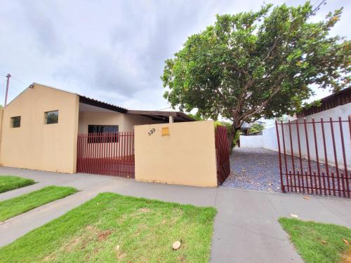 a house with a red fence and a tree at Residencial da Praça in Bonito