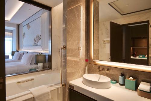a bathroom with a sink and a tub and a bed at Sofitel Xiong An in Baoding