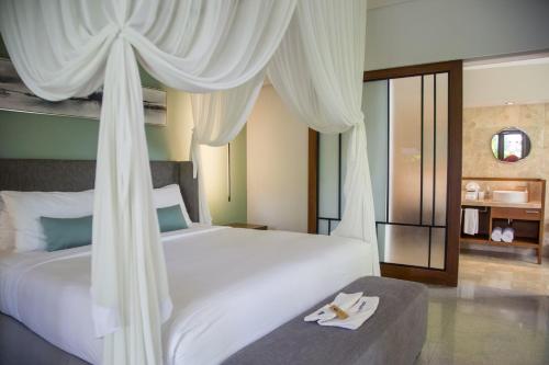 a bedroom with a large white bed with curtains at The Amala Boutique Retreat in Seminyak