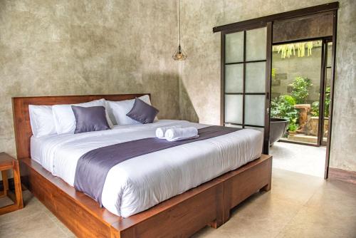 ein Schlafzimmer mit einem großen Bett mit einem Holzrahmen in der Unterkunft VILLARIZ Ubud , Bali in Ubud