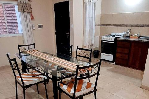 La cocina está equipada con mesa de cristal, sillas y fogones. en Depto. céntrico en CatamarcaCity en San Fernando del Valle de Catamarca