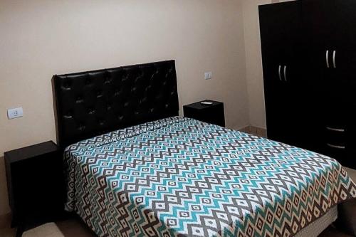 1 dormitorio con 1 cama con cabecera negra en Depto. céntrico en CatamarcaCity en San Fernando del Valle de Catamarca