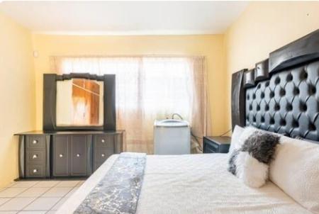 a bedroom with a bed with a black headboard and a television at Revive Haven Guesthouse in Roodepoort