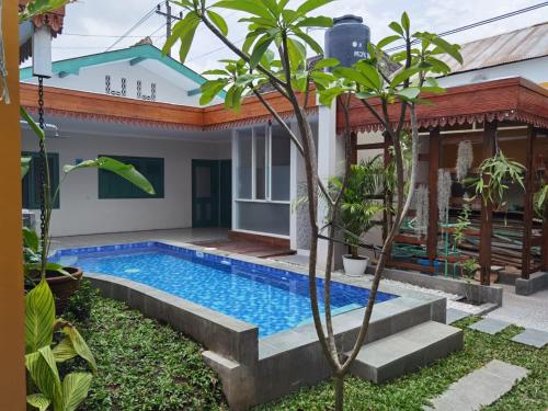 a villa with a swimming pool in front of a house at Ndalem Kinasih Homestay Syariah in Solo