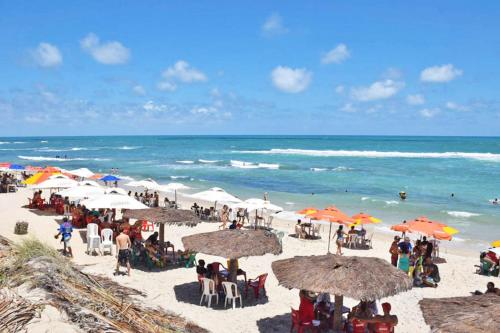 SibaumaにあるChalé A GRANDE FAMÍLIA Praia de Sibaumaの傘をさして浜辺に座る人々