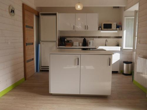 une cuisine avec des armoires blanches et un réfrigérateur blanc dans l'établissement Maison cosy avec jardin, centre de Sauzon, 200m du port, 3 chambres, WiFi, terrasse et barbecue - FR-1-418-211, à Sauzon