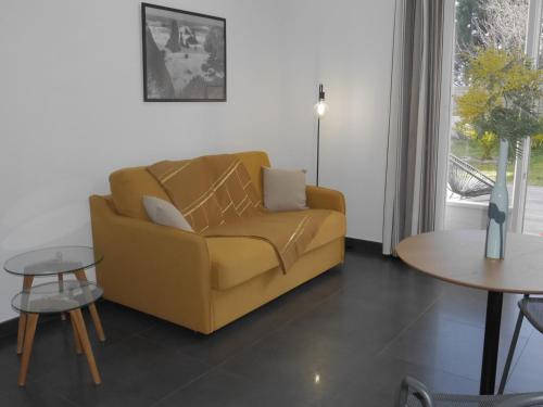 un salon avec un canapé jaune et une table dans l'établissement Maison moderne et calme avec jardin, proche mer - Locmaria - FR-1-418-223, à Locmaria
