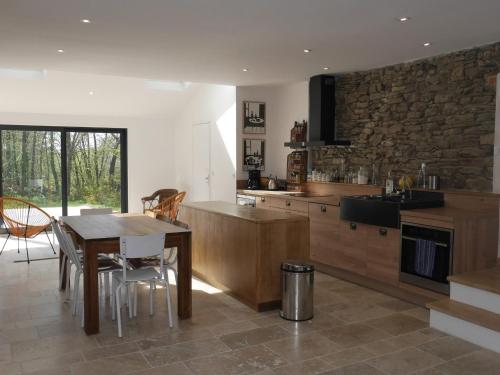 - une cuisine avec une table et un mur en pierre dans l'établissement Villa Contemporaine avec Jardin, à 1,5 km de la Plage: 8 pers., 2 Terrasses, Wi-Fi, Baignoire Balnéo - FR-1-418-198, à Locmaria