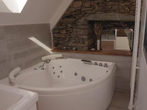 a white bath tub in a bathroom with a stone wall at Maison contemporaine au calme près de la plage, WiFi inclus - FR-1-418-198 in Locmaria