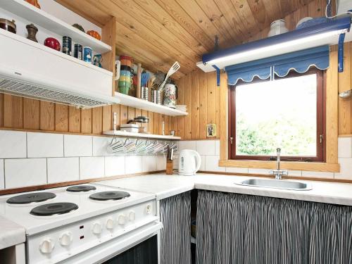 a kitchen with a stove and a sink and a window at 6 person holiday home in Dannemare in Dannemare