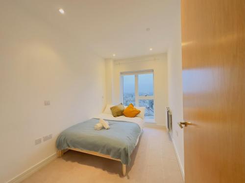 a bedroom with a bed with orange pillows and a window at Luxurious Comfy Penthouse - Steps to East Croydon Train Station - Views in Croydon