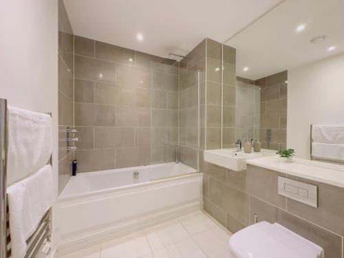 a bathroom with a tub and a toilet and a sink at Luxurious Comfy Penthouse - Steps to East Croydon Train Station - Views in Croydon