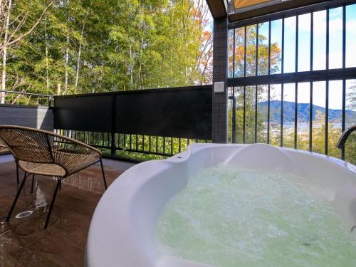 a bath tub sitting next to a chair and a window at Bettei Fujiya in Miyajima